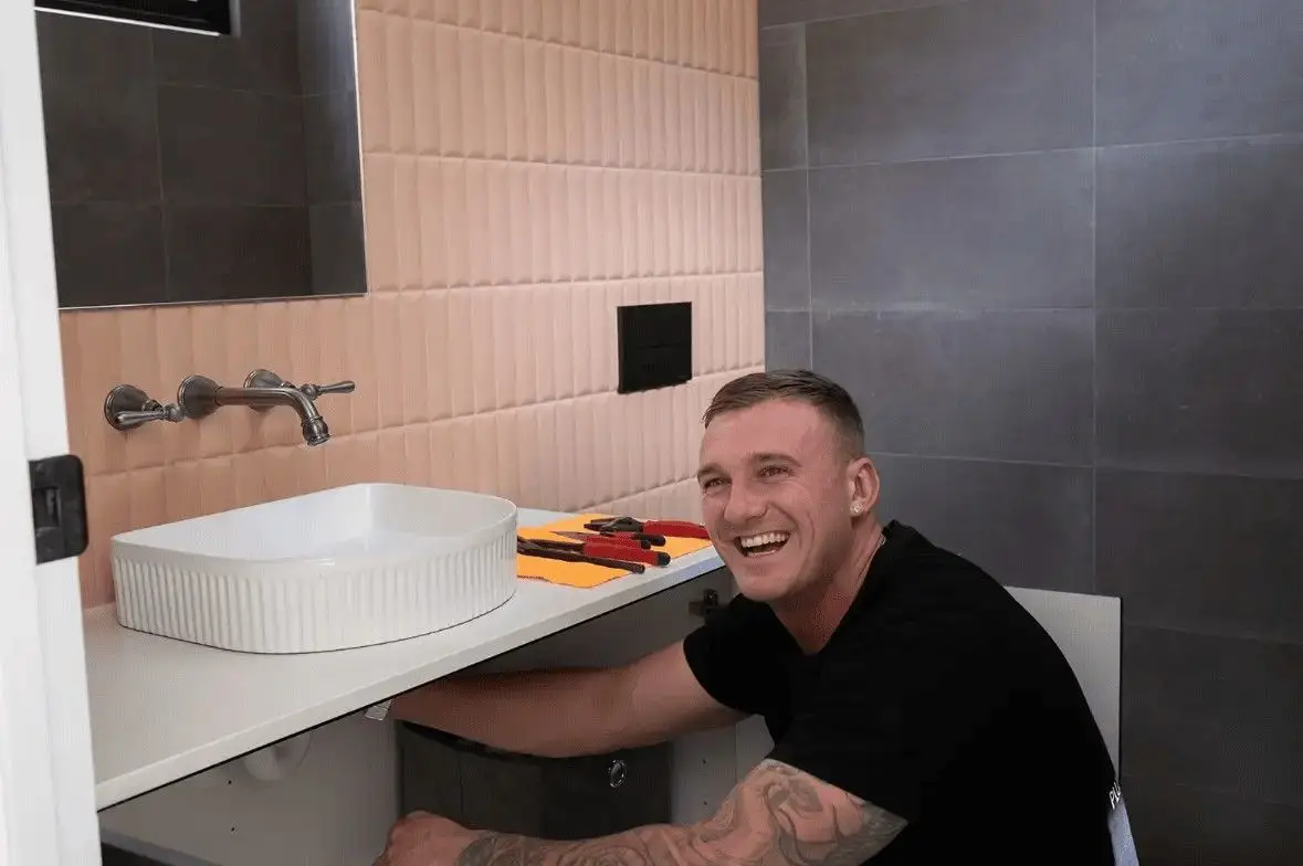 Steven Seery working on the plumbing under a new bathroom basin