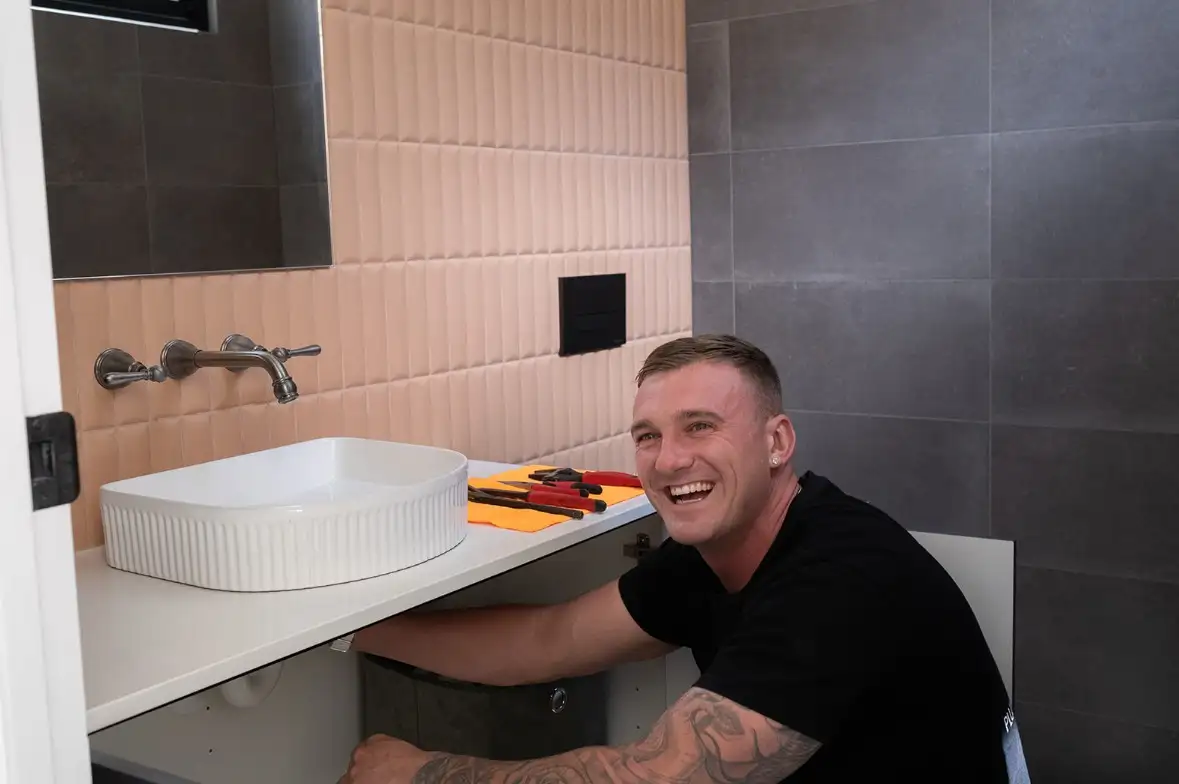 Commercial plumbing installation inside Adelaide retail premises. – Steven fixing sink underneath plumb ezy co Reliable Adelaide plumbing services for commercial and residential projects.