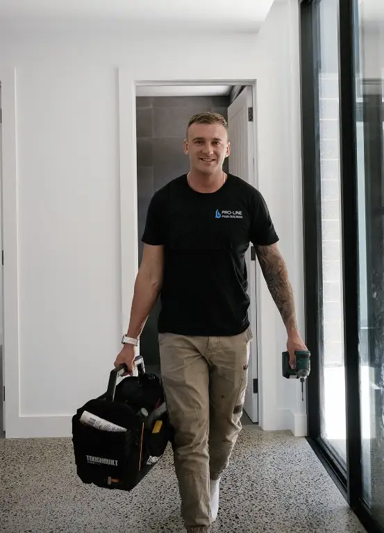 Adelaide plumbing contractor discussing project details with commercial client. Steven owner of Proline walking in hallway holding plumbing bag.